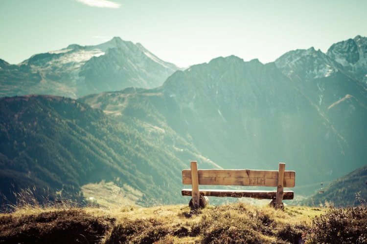 Eine Holzbank in den Bergen mit Aussicht auf die Berge und Täler