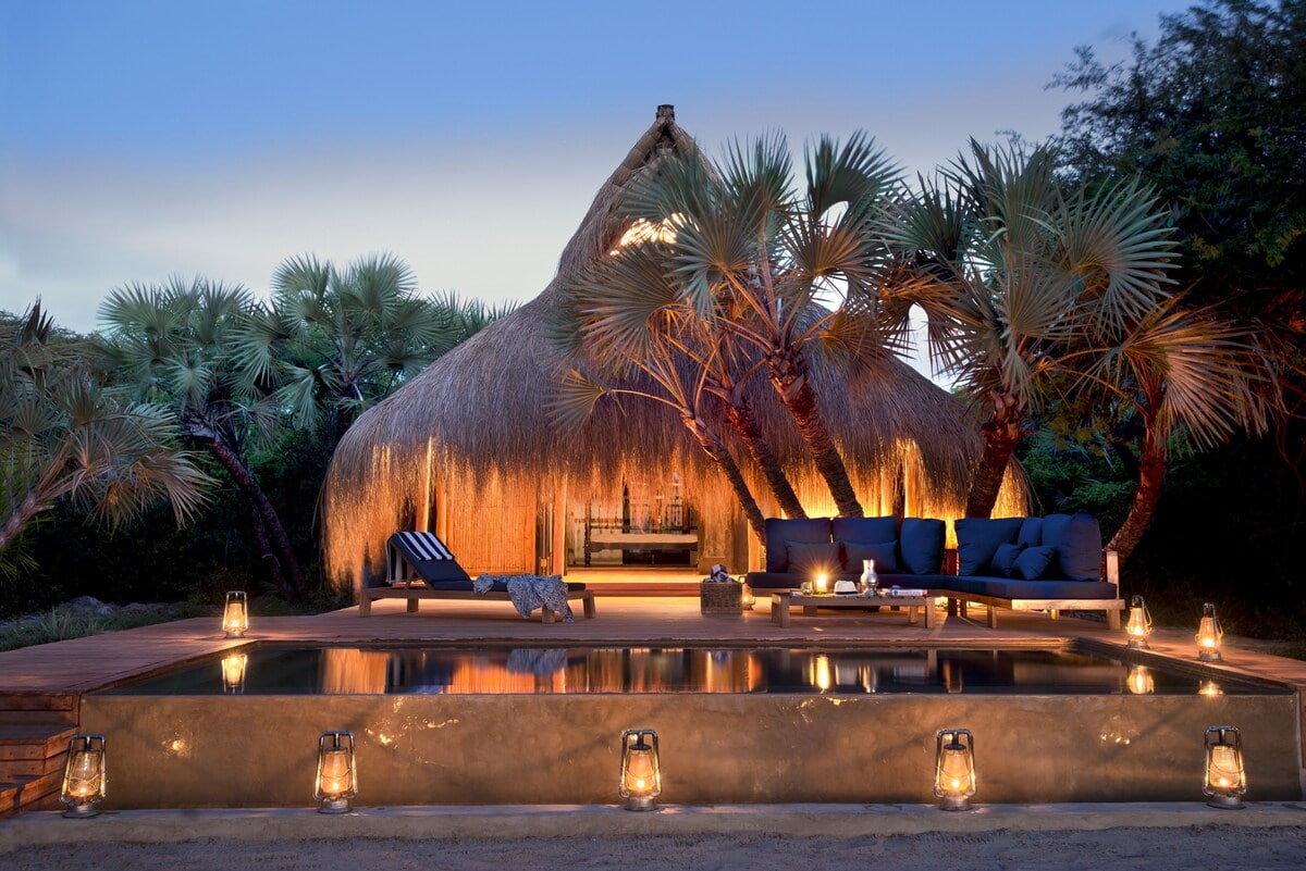 Privater Pool einer Strandvilla mit Liegestühlen und Palmen im Hintergrund