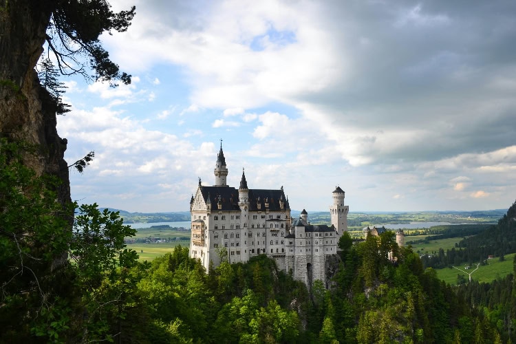 Schloss Neuschwanstein in Bayern, über grünen Wäldern mit Blick ins Tal.