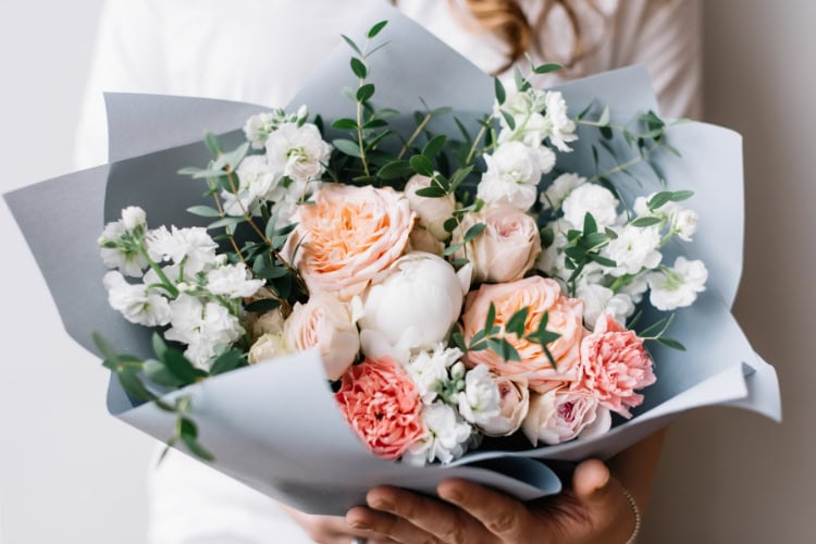 Eine Frau zeigt einen Strauß bunter Blumen in ihrer Hand
