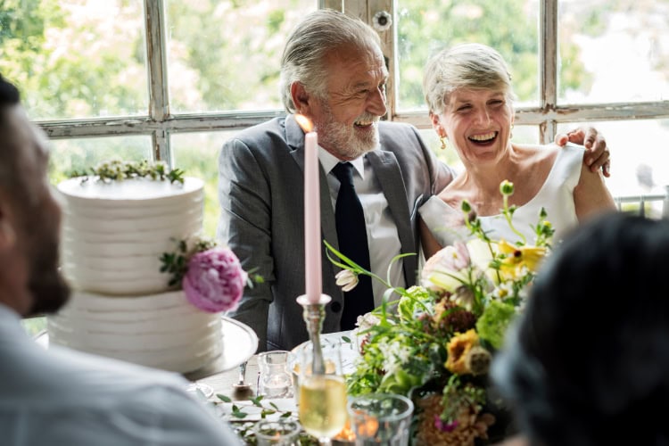 Ein älteres Paar sitzt nebeneinander und hält sich an den Händen.