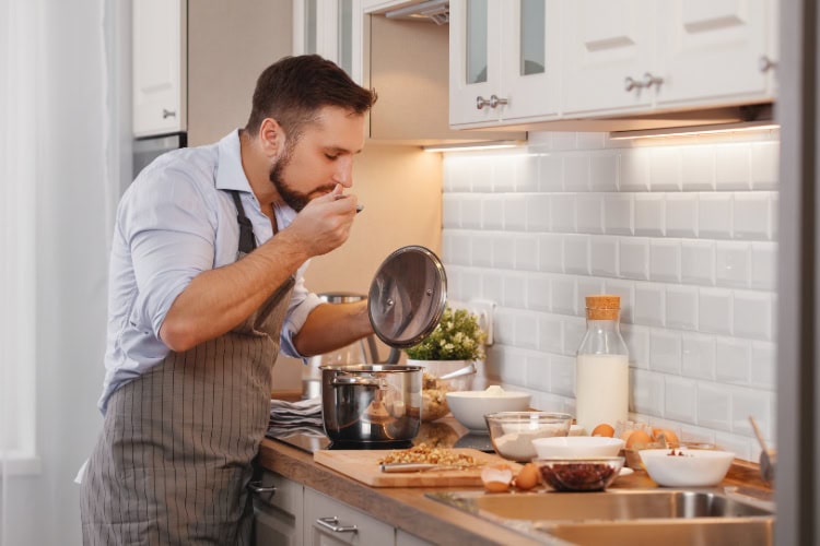 Ein Mann steht in der Küche und kocht an einem Herd.