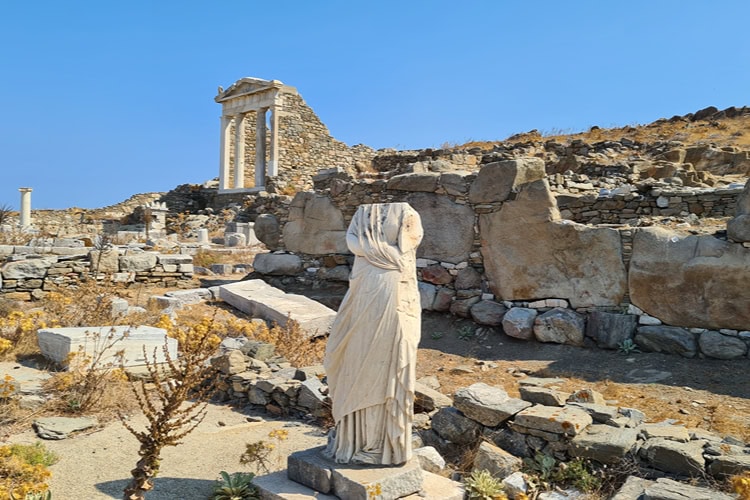 Antike Statue vor Tempelruinen auf der Insel Delos bei Mykonos – ein beliebtes Ziel für Kulturinteressierte.