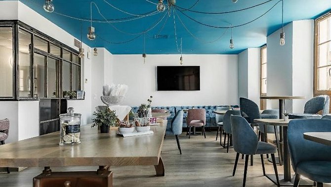 Offener Frühstücksbereich mit Buffet, modernen Sitzmöbeln und markantem blauen Deckendesign im Hotel The Originals Boutique