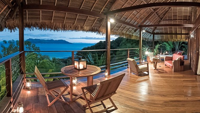 Die große überdachte Veranda mit Sitzgelegenheiten, Tischen und Blick über den Regenwald und das Meer