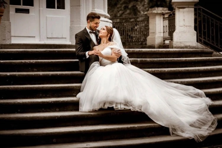 Brautpaar sitzt auf einer Treppe und schaut sich verliebt an