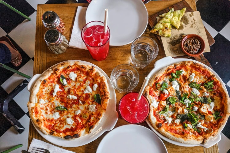 Gedeckter Tisch im Restaurant mit zwei Pizzen und Getränken